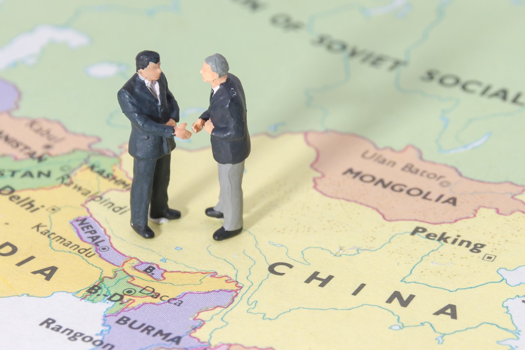 Miniature Businessmen Figurines Shake Hands on China Map